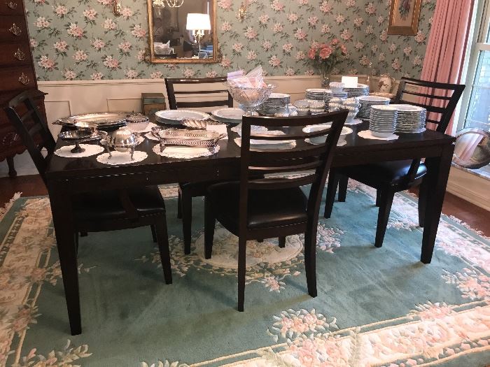 Dining Room Table with 4 chairs - Modern style Espresso color (Almost Black), shown as a rectangle with the leaf in. Additionally, there is a large oriental area rug in this photo. 