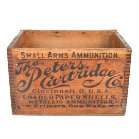 Vintage Peters Cartridge Company Ammunition Crate: A vintage The Peters Cartridge Co. wooden ammunition crate. The rectangular crate has dovetail construction to the corners. It is marked on all sides and has carved grooves for handles to the sides. This Cincinnati based company sold small arms ammunition and gunpowder production. The building was built in 1916 and added to the National Register of Historic Places in 1985.