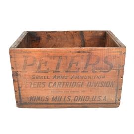 Vintage Peters Ammunition Crate: A vintage The Peters Cartridge Co. wooden crate. The rectangular crate has dovetail construction to the corners. It is marked on all sides and has carved grooves for handles to the sides. This Cincinnati based company sold small arms ammunition and gunpowder production. The building was built in 1916 and added to the National Register of Historic Places in 1985.