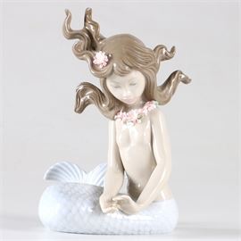 Lladro Porcelain "Mirage" Mermaid Figurine: A Lladro figurine. The piece depicts a mermaid with her hair flying and studying her cupped hands. The piece is titled Mirage. The piece has printed marks in under glaze blue reading “Lladro Handmade in Spain” together impressed and incised workmen’s marks.
