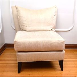 Upholstered Slipper Chair: An upholstered slipper chair. This chair features a straight crest rail with a dip to the center over a square back. The removable seat cushion rests over a straight apron that rise on four french feet. Included is a pillow in coordinating upholstery fabric. There is a tag to the chair with the marking “Swaim Upholstery.”