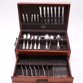 Swedish C. G. Hallberg Silver Plate Flatware in Case: A group of silver plate flatware by Swedish maker, C. G. Hallberg. This includes eleven dinner forks, nine salad forks, four dessert forks, eleven tablespoons, two teaspoons, nine steak knives, ten dinner knives, and twelve butter knives. They contain scalloped edges to the handles.