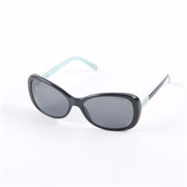Tiffany & Co. Sunglasses: A pair of Tiffany & Co. sunglasses. The pair offers black frames with Tiffany blue and black temples. They are marked throughout with the Tiffany & Co. logo and are accompanied by a Tiffany blue sunglasses case.