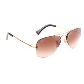 Ray-Ban Aviator Sunglasses: A pair of rimless Ray-Ban aviator sunglasses. The pair features dark brown tinted lensed and gold tone arms. One lens is marked with the Ray-Ban name to the upper edge. They are accompanied by a case and a lens cleaning cloth.