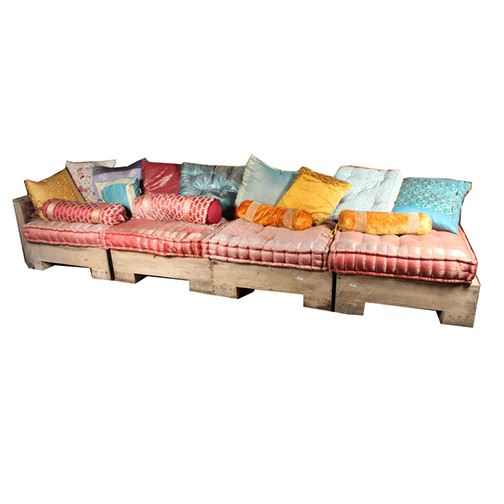 Teak Wood Outdoor Sectional Couch: A teak wood outdoor sectional couch. This set includes four square back pieces with square seat resting on bracket feet. One piece features a tall armrest. This set includes decorative seat cushions and accent pillows. There are no visible maker’s marks or labels on these pieces.