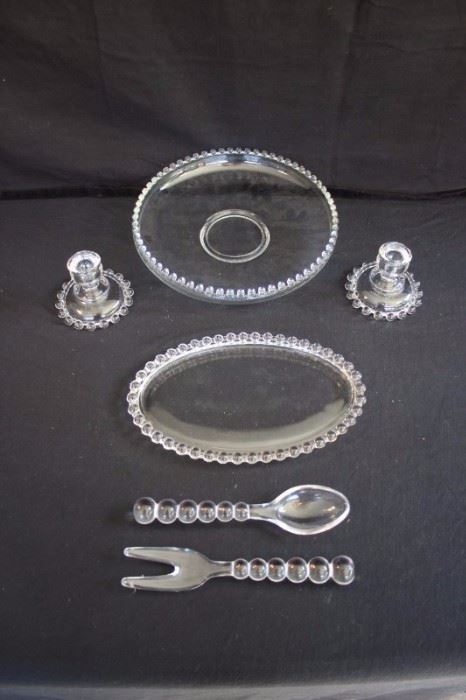 Clear Hostess Set: including 12" float bowl & 10" salad servers by Imperial of OHIO, Candlewick pattern, and pair of 4-1/2" candlesticks and oval 12" dish by Anchor Hocking. This lot is in very good condition and shows little wear, if any.