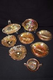 8 Pieces of Amber Carnival Glass: 4 divided bowls (8"), 1 handled candy dish (4.5"), 1 oval relish dish (9.5"), 2 leaf and berry pattern rounded triangular shaped with original Woolworth price tag (7"). This lot is in very good condition and shows little wear, if any.