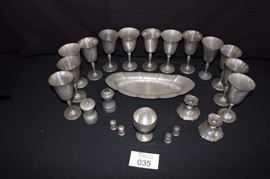 23 Piece Genuine Pewter Set:  4 Genuine Pewter wine glasses with knobbed stems (7"); 9 Genuine Pewter wine glasses with slim stems (7"); a pair of short colonial Pewter candlesticks 1900-1950 (2.5" H); 2 pairs of individual Pewter salt and pepper shakers (1.5"); salt shaker and pepper mill (made in Italy); Oval bread serving dish (14"); and a squatty goblet (4.25"). in good vintage condition. It has a nice vintage patina. There are signs of wear with some scratches and dents. Good condition but about 4 glasses could be reshaped, which is quite easy ... sit piece(s) out in the sun and pewter becomes very pliable.