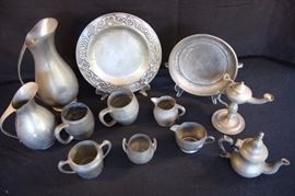 Genuine Pewter 15 Pieces w/ Monk Lamp: Individual tea pot with Hornet hallmark on bottom ( 6"H); 2 Solid Pewter mugs (4"); 4 miscellaneous cream and sugars; 1 hammered Marion Pewter 700 handled sugar); 1 creamer marked Genuine Pewter B W 1 2; sugar marked Concord with hallmark of K inside of a tower and 72; small Pewter ewer pitcher marked Etain Pur Tiel Holland G X K (7.75"H); large Pewter ewer Pitcher marked Royal Holland Daalderop K M over D  (11.5"H) this pitcher is dinged and misshapen; handled Pewter dish (8.5"); Art Deco serving plate (10.5"); and Pewter Monk Lamp, circa 18th C/ German.  Good condition; there are signs of wear with some scratches and dents. Reshaping is quite easy ... sit piece(s) out in the sun and pewter becomes very pliable.