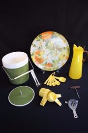 Mid-Century Modern Bar Set" B85Green handled ice bucket with ice tongs in very good condition, 14" floral plastic ware,  hand blown yellow martini pitcher with glass stirrer, 5 Tupperware measuring cups, 6 Tupperware measuring spoons, bar martini shaker and corkscrew marked Japan. This lot is in very good condition and shows little wear, if any.