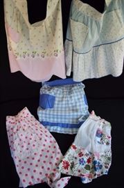 Pastel Vintage Handmade Aprons:  All in good vintage condition 2; 1 child's apron with 2 side pockets made with white organdy and floral piquet fabric etched with white rick-rack (light stain) , 1 light blue apron with 2 front pockets with mini floral on white background trimmed with rick-rack and edged with blue bias tape, 1 blue gingham with 2 front pockets trimmed with blue cotton (small spot on pocket) 1 white & lavender apron with 1 pocket (a slight stain), 1 white with pink polka dots with 1 pocket edged with white eyelet (tiny spots).  Other than two mentioned above, all are in very good vintage condition
