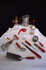 12-Piece 1940-50's Red Kitchen Utensils: 1 8-ounce glass and aluminum nut chopper marked Dispensers Inc. Los Angeles-New York 23062A; 7.5" mini grater with 4.5" glass container, plastic top marked for teaspoons and tablespoons with metal grater; 9" strainer with red & white plastic handles; 8.5" ice pick with red wooden handle; 6" apple corer / butter pat maker marked "Nut-brown" Made in England Butter pat maker and apple corer; 6.5" knife sharpener with wooden handle Dubla Made in USA Patented; 12" kitchen knife with 8" blade plastic handle, marked Ouihut Sh Freeze Proce Stainless; 10" spatula with Bakelite handle, marked made in USA, spatula is marked Englishtown marquee Stainless Steel; 6.5" 5-cup Brite-Pride sifter marked Visible Measure Flour Sifter Sifts Aerates, Fluffs Made in USA; 6" glass syrup container with plastic lid marked Made in USA; 12" rotary hand mixer with wooden handles The Taplin Mfg. Co. New Britain, Conn. Pat. No. 1518285 Made in USA.Some have wear of paint and 