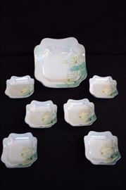 Art Nouveau Berry Set:  8.25" serving bowl with  six 4.5" individual bowls, hand painted with white yellow shaded lilies with shades of blue accents on a teal splash with a  mother-of-pearl shimmer and silver edges. This lot is in very good condition and shows little wear, if any - no chips or cracks.