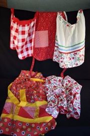 Handmade Vintage Apron Lot of 5: red & pink flowers with green leaves on white background cobblers apron with 2 pockets, buttons at the neck; red & white gingham and red, black & white handkerchief print reversible full apron with 1 pocket on each side; handmade long full hostess apron  in cute daisy print with mini polka dots trimmed in bright yellow with quilted 5.25" inset which is 33.25" from waist to hem / no pocket; white with green, blue and red bias insets with cherry/strawberry and floral waistband and border at the hem / no pocket; smaller half apron with  ties and waistband which measure 58.5", body of apron is 1.5" red & white gingham/ no pocket. All in good vintage condition, no rips, stains or holes.