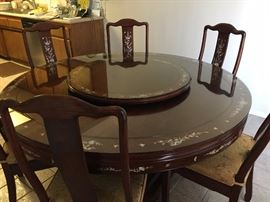 Rosewood Dining Table and 6 Chairs with beautiful Mother of Pearl Inlay Pattern.  A matching Lazy Susan is included and both the table and the Lazy Susan have glass covers.  This set is in excellent condition.  The table is 5' diameter.