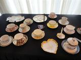 a collection in the foyer cups and saucers and other hand painted pieces