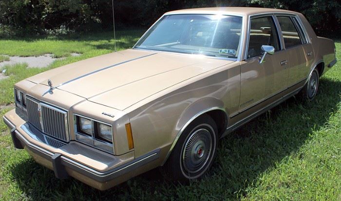 At 8PM: 1986 Pontiac Bonneville Estate Auto with 84,590 Odometer Reading; Gold Metallic Exterior, Tan Cloth Interior; AM/FM Stereo; Air Conditioning; Clean & Well Maintained. VIN: 2G2GN69A0G2288422