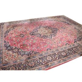 Large Hand-Knotted Persian Kashmar Area Rug: A large hand-knotted Persian Kashmar rug. The central medallion with pendants is surrounded by deep blue infilled with pomegranates, flowers, and arabesques. The field is scarlet and is densely populated by stylized flowers, vining foliage, and palmettes in a palette of deep blue, bright blue, gold, tan, pink, rose, gray, taupe, and green. The spandrels are deep blue with similar designs in the same shades with tan predominant in the corners, The inner and outer guard borders are bright blue with repeating floral designs while the primary border reiterates the herati patterns and colors found in the central lozenge and in the spandrels. It has overcast edges with protective strips to the underside with thick cotton warp fringe. Tagged to reverse.