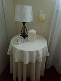 Small accent table with cloth. Also shown, glass clock, candle holder and lamp