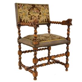 Vintage William and Mary Style Needle Point Arm Chair: A vintage William and Mary style needle point arm chair. This chair features a straight crest rail with needle point upholstered rectangular back panel and barley twist arms with lion handholds rising on a single support. The square seat is upholstered and rises on turned legs joined by stretchers and terminating on ball feet. This piece features a fruit and floral pattern needle point upholstery. There are no visible maker’s marks. For matching side chairs, see item 17LOU097-087.