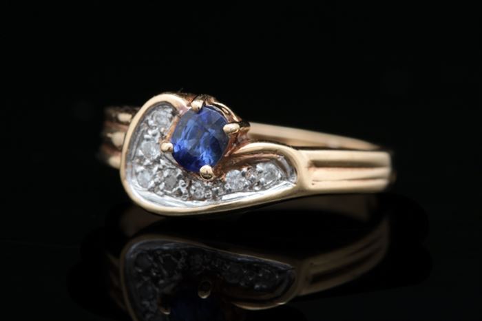 14K Two-Tone Gold, Blue Sapphire, and Diamond Ring: A 14K two-tone gold, blue sapphire and diamond ring featuring an oval, prong-set blue sapphire accented with seven round brilliant diamonds set with 14K white gold prongs.