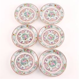 Circa 1970s Hong Kong Exportware Porcelain Plates: A set of six circa 1970 hand painted porcelain plates. These feature shou medallions surrounded by intertwining pink blossoms and green foliates in the center, and alternating floral and leiwin decoration on the flaring rims. Each piece is marked underneath in red “Japanese Porcelain Ware”, “Decorated in Hong Kong”, and “A.C.F”.
