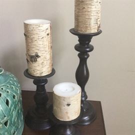Pottery Barn Pillar Birch Candles and Pedestal Holders: A selection of pillar birch candles and wooden pedestal holders from Pottery Barn. This lot features three wooden pedestal holders, the tallest with ring- and vase-turns in the stem, and each with round tops that have slightly ridged edges. They have felt covered undersides marked “Pottery Barn”. Also included are three white pillar candles with a birch bark style wrap.