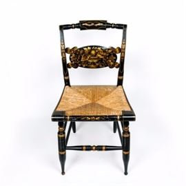 Authentic Vintage Hitchcock Painted Chair: An authentic vintage Hitchcock painted chair. This vintage 1980s chair has a wooden frame and woven, straw seat. The frame is painted black with an ornate gold-toned floral and fruit motif painted across the seat back, legs, and edging. Along the back of the seat, the chair is marked Hitchcock in stenciling.