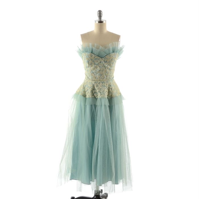 Circa 1950s Party Dress: A circa 1950s party dress. This aqua taffeta dress features a sweetheart neckline, fitted waist, and hidden back zip closure, with a cream lace overlay to the bodice and peplum, aqua tulle overlay and embellished with tiers of pleated tulle to the neckline and peplum. The interior is unlined, with boned support to the bodice, and unmarked.