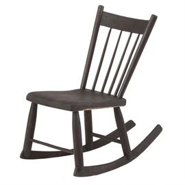 Rustic Rocking Chair: A rustic rocking chair. This chair has a dark brown stain and a spindle back. It is unmarked.