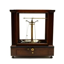 Christian Becker Chemistry Scale: A Christian Becker chemistry scale. This vintage piece has several different accessories and pieces included. There is a drawer on the front with other items and directions inside. There is a crack to the black glass inside the bottom of the piece. The large front and back glass panels lift out through the top. There is a registration form in the drawer. It stands on adjustable brass feet.