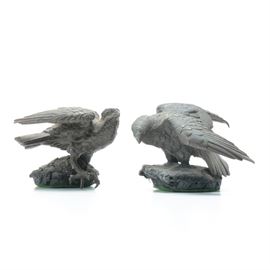 Metal Covered Birds of Prey Figurines: A pair of metal-covered birds of prey figurines. These figurines are shaped like falcons or hawks, perched on a faux stone base, with their wings slightly raised. The undersides of the bases are covered in green felt.