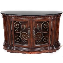 Contemporary Marble Top Demilune Sideboard: A contemporary ornate demilune sideboard with a black marble top. The sideboard has two front doors framing metallic openwork decorations and ornate scrolling brass knobs. It has a serpentine shape with a dentil top molding and multiple tiered lower molding.
