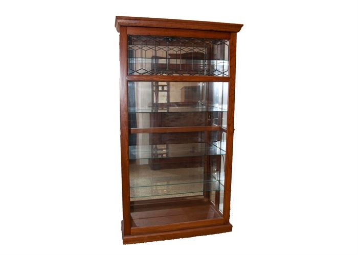 Lighted Curio Cabinet: A traditional lighted curio cabinet. This lovely cabinet features a wood frame in a warm cherry finish and a sliding lockable glass front door with decorative diamond and hexagon shaped metal piping to the top.The interior boasts four adjustable glass shelves with grooves for displaying plates and a mirrored back.