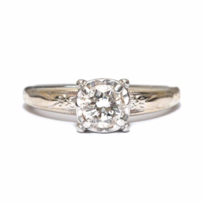 14K Platinum and Diamond Solitaire Engagement Ring: A 14K platinum, engagement ring setting that has a raised foliate detail at the shoulders and a prong-set diamond solitaire stone to center.