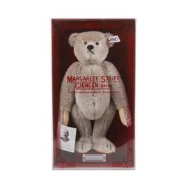 Margarete Steiff Teddy Bear with Original Box: A reproduction vintage “Teddybärr – Modell 1902” Steiff teddy bear, designed by Richard Steiff, the nephew of the company founder Margarete Steiff. The bear is made of light gray-brown wool blend mohair, with tan felt paws, glass or plastic eyes, and an embroidered nose and mouth. The bear has a button and tag in its left ear, marked with number “0150/32”, and it also comes with a sewn in fabric tag marked with the fabric content, and “Made in Western-Germany”. A paper tag is attached to the bear’s right paw, and it comes in the original box marked “Margarete Steiff Giengen-Brenz”.