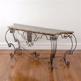 Louis XV Inspired Faux Marble Top Metal Console Table: A Louis XV inspired faux marble top metal console table. This piece features a painted faux marble top in brown and beige hues. The top is rectangular, with notched sides and a beveled edge. The top rests on a bronze-toned metal base, with an apron featuring an oval panel with an embossed double fleur-de-lis motif. The table rises on four scrolling legs, with a scrolling stretcher with an arrow finial.