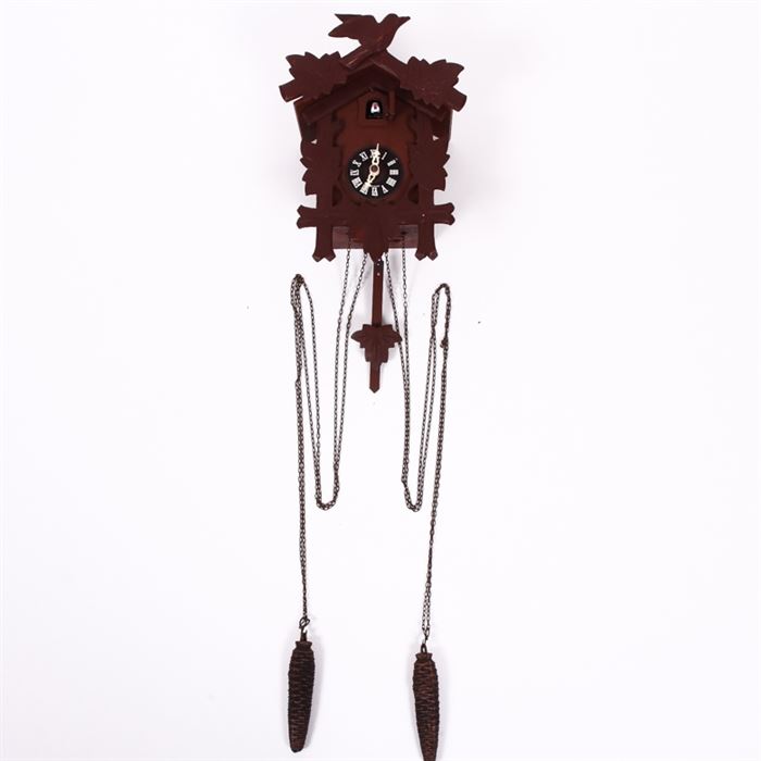 Vintage German Black Forest Style Cuckoo Clock: A vintage German Black Forest style cuckoo clock. This clock features a wood frame with hand carved maple leaves and a bird perched at the top, right above a small hand painted cuckoo bird that emerges when the clock strikes the hour. Two pine cone weights and a leaf pendulum hang from the bottom. The clock face is marked “Germany” and the verso of the piece is stamped “Made in Germany”. The pine cones are marked “275 ET”.