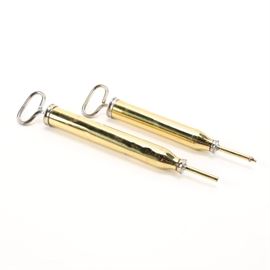 Brass Cylindrical Air Pumps: A pair of vintage brass cylindrical air pumps. This pairing includes two pumps with slender cylindrical bodies and silver tone looped handles. These items are unmarked by designer or distributor.