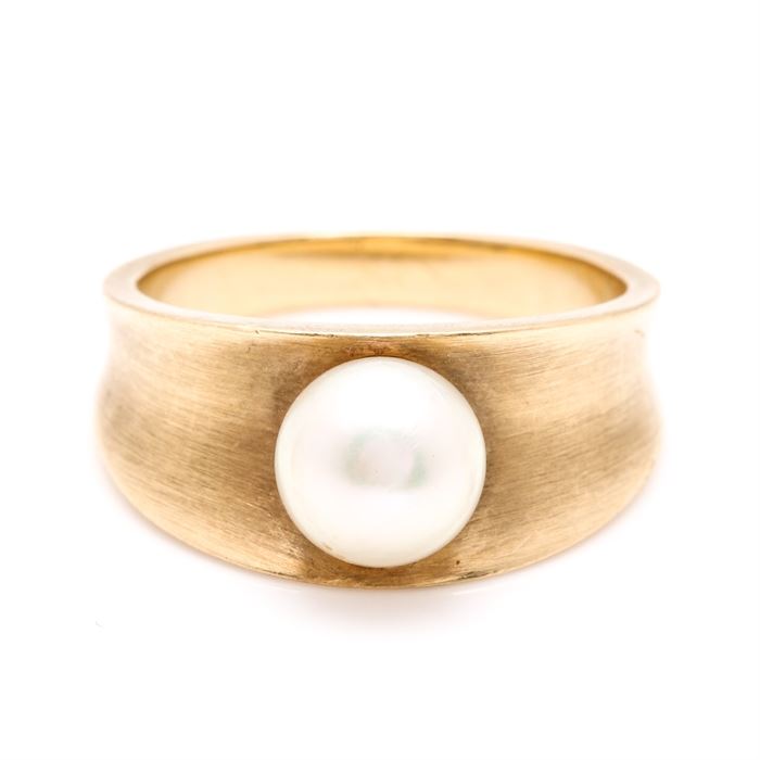 18K Yellow Gold Cultured Pearl Ring: An 18K yellow gold cultured pearl ring. This features a ring with a cultured pearl centerpiece resting in a valley between two raised borders.
