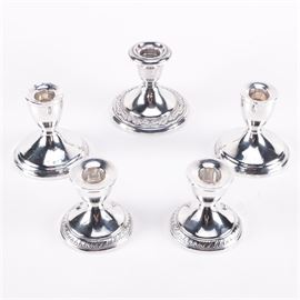 Weighted Sterling Candlesticks: A set of weighted sterling candlesticks. This selection of weighted sterling candlesticks features bell shaped cups with flared rims, tapered stems, and weighted round bases. Pieces are marked to the undersides.