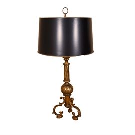 Brass Tone Table Lamp: A brass table lamp with a twisted, reeded base. The lamp sits on three arching feet and is topped with a black drum shade with brass circle finial.