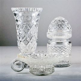 Assorted Crystal Pieces Including Waterford: An assortment of crystal pieces including Waterford. This selection of crystal pieces features a cylindrical vase with wide mouth and diamond motif on a round base, a lidded jar with rounded lid and all over diamond motif and a small handled taper style candle holder with starburst motif. Pieces are marked to the undersides.