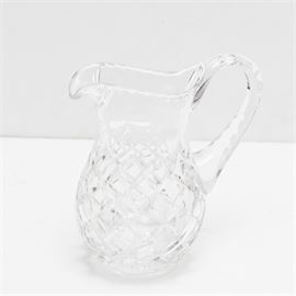 Waterford Crystal Pitcher: A Waterford Crystal pitcher. The pitcher features a thumb print design to the rim, handles, and shoulder and cross cut designs to the body. Maker’s mark to the underside.
