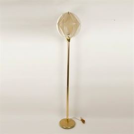 Mid-Century Modern String and Lucite Floor Lamp: A midcentury modern styled floor lamp. This lamp has a brass colored round metal base, a pole shaped body and a round ball shaped top. The top shade part is created out of pieces of cut lucite that have been wrapped in string to create a patterned shade of sorts for the bulb.