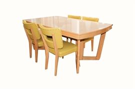 Mid Century Modern Blonde Dining Table and Chairs by Meier Pohlmann: A blonde Mid Century Modern dining table and chairs by Meier Pohlmann. This table features a formica top styled to match the natural blonde wood of the rest of the table, which is balanced on open-work geometric legs. The four chairs are in a matching blonde wood, with open-work backs, lime green textured upholstery, and naill-head accents.