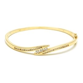 14K Yellow Gold Diamond Hinged Bangle Bracelet: A 14K yellow gold diamond hinged bangle bracelet comprising 1.00 ctw in tension set and channel set round brilliant cut diamonds.
