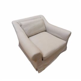Restoration Hardware Armchair: A linen slipcover armchair. This piece has a beige linen slipcover style upholstery. It has a pillow back, swooping rolled arms, and a square seat. To the bottom is a full skirt. For a coordinating piece, see item 17NAS083-003 and 17NAS005.