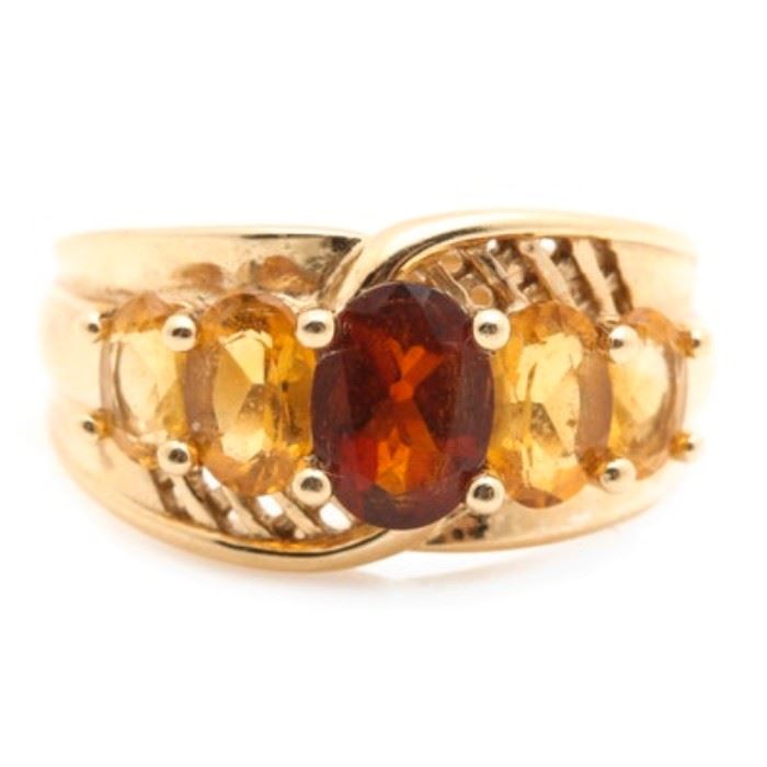 14K Yellow Gold Garnet and Citrine Ring: A 14K yellow gold garnet and citrine ring. This ring features a center prong set oval garnet stone flanked by prong set citrine stones and accented with pierced lattice detail.