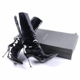 Gucci Patent Leather Stiletto Boots: A pair of Gucci stiletto boots. This style features a black patent leather knee high upper with a structured shaft, pointed toe, decorative front stitching, silver tone stiletto heels and black soles. The boots are a size 8 and are “Gucci” to the soles.